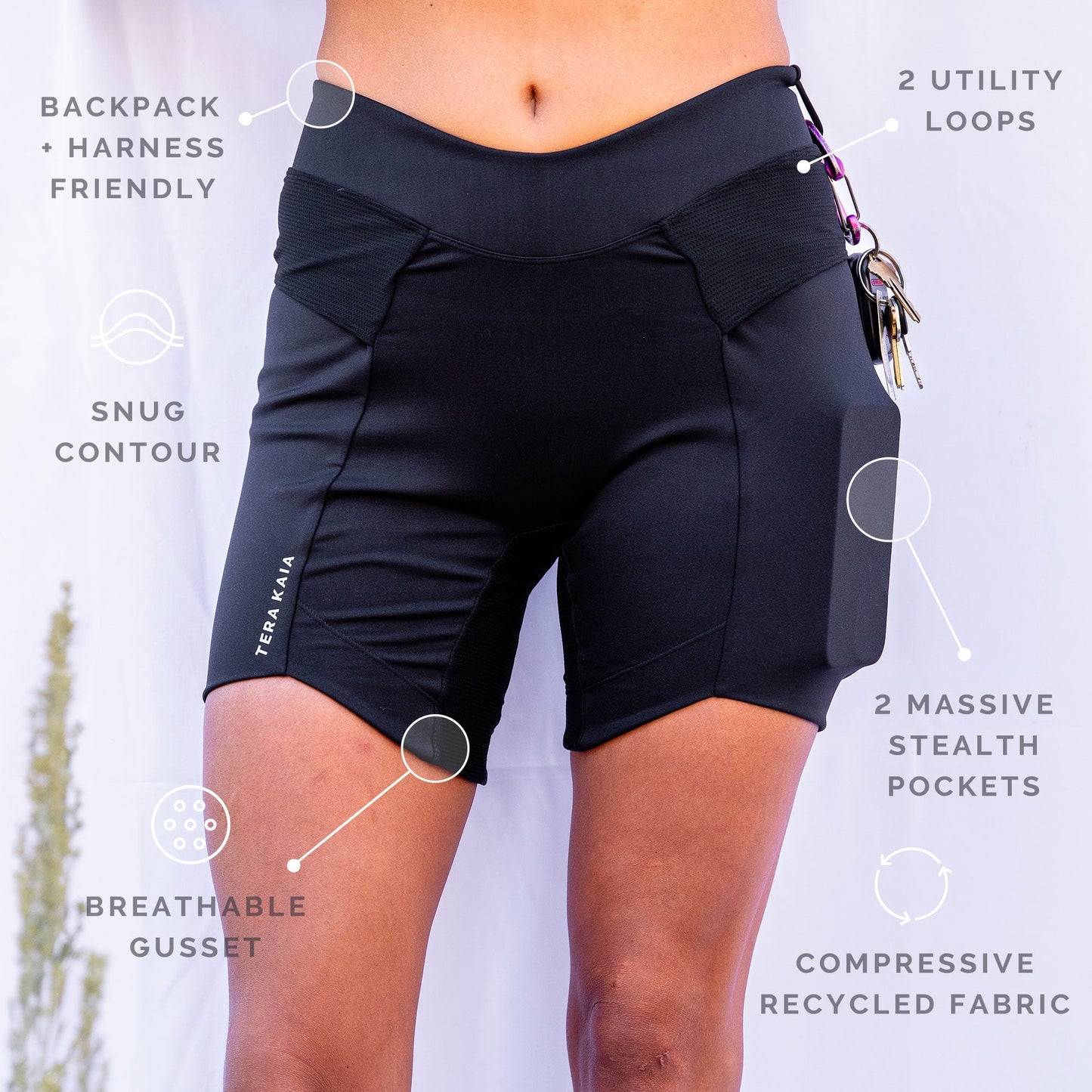 Front closup view of black toura short identifying features of backpack harness friendly, 2 utility loops snug contour, 2 massive stealth pockets, breathable gusset, and compressive recycled fabric.