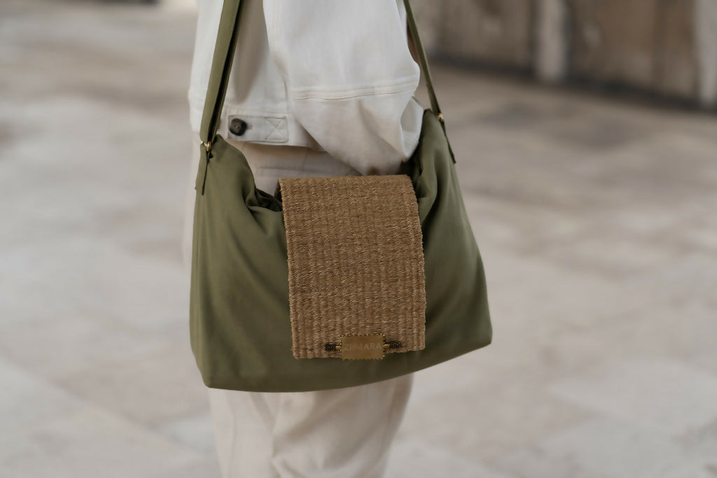 Partial side view of person wearing white, and large green bag with sisal details.