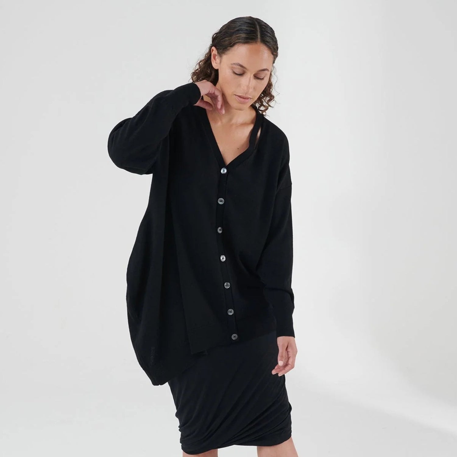 Woman in black long cardigan and black dress with buttons down the center.