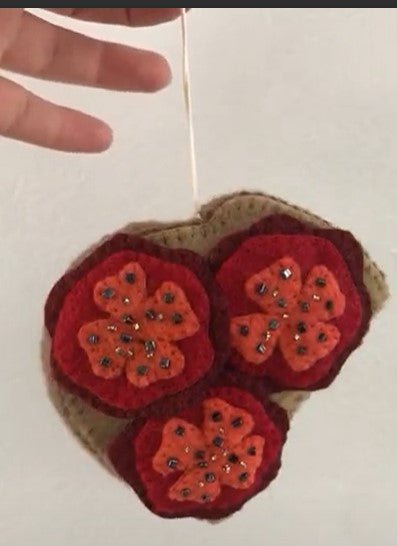 Close up of felt ornament of three tomato slices on toast.