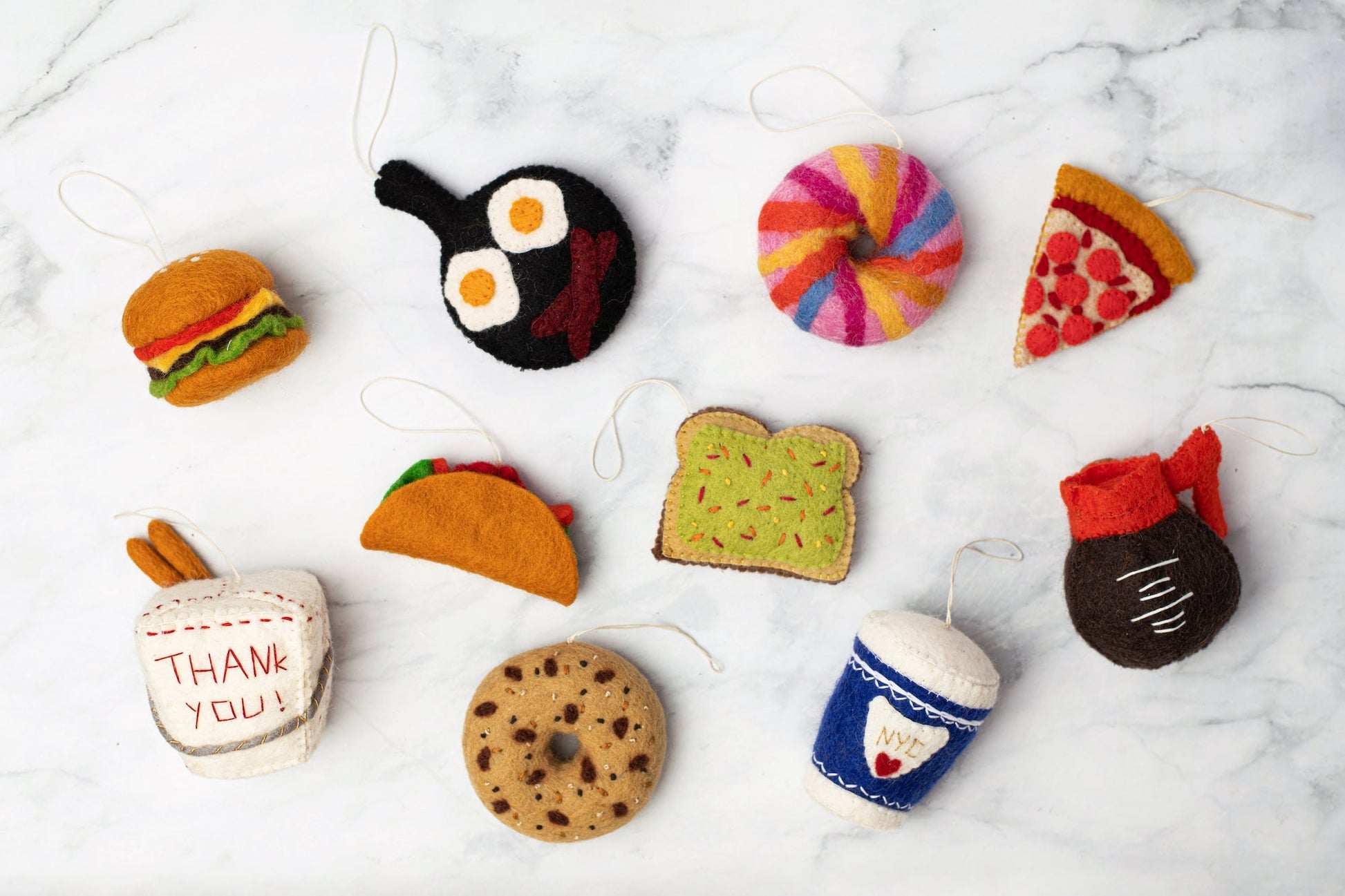 Felt ornament of a fry pan with eggs and bacon in it with other scattered food ornaments.