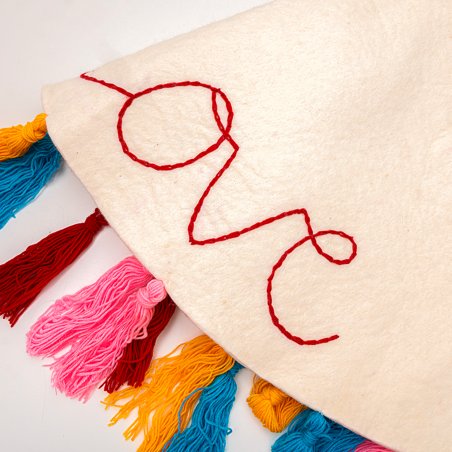 Close up of the embroidered word 'love" on a white felt Christmas tree skirt.