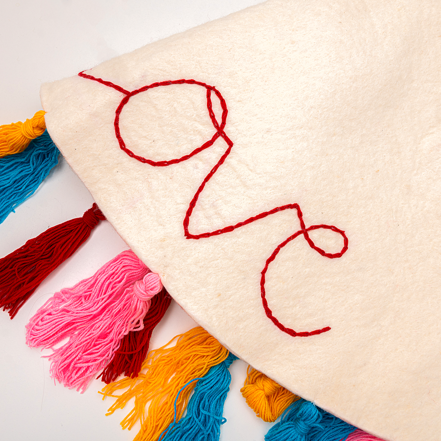 Close up of the embroidered word 'love" on a white felt Christmas tree skirt.