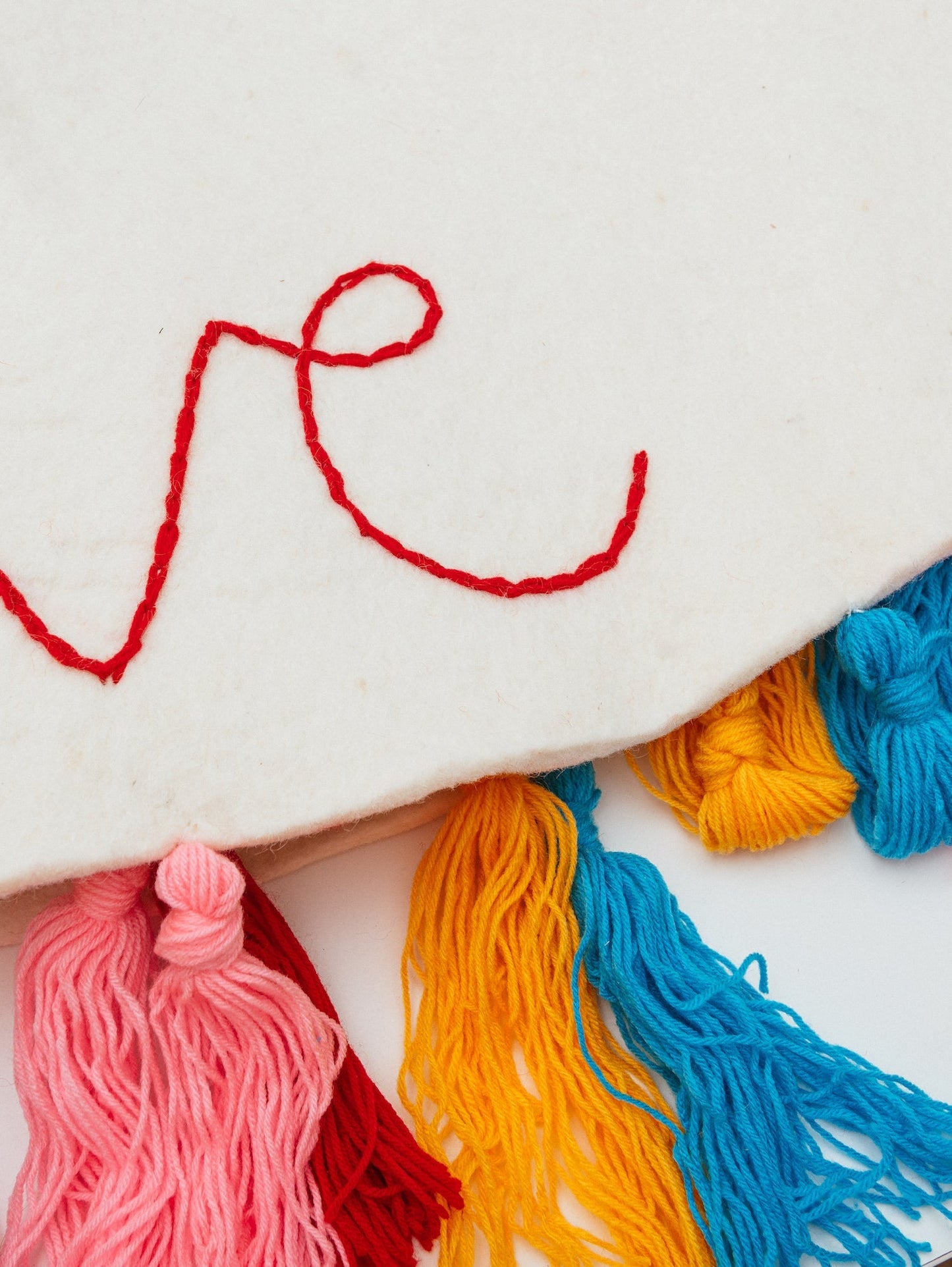Close up of the embroidered word 'love" on a white felt Christmas tree skirt.