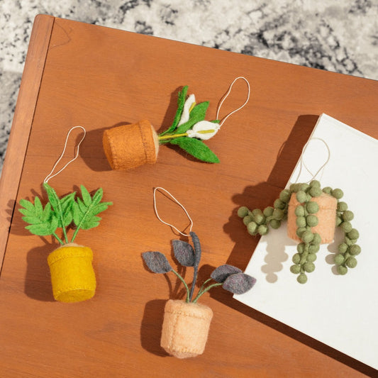 Scattered felt ornaments of a Peace Lily, Parlor Palm, Rubber Plant, and String of Pearls plant in pots.