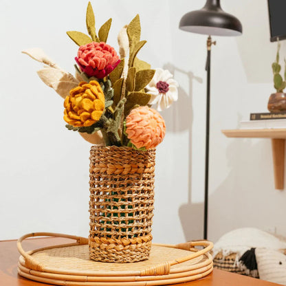 Dusty pink, orange, and yellow felt flowers in white vase with various other flowers.