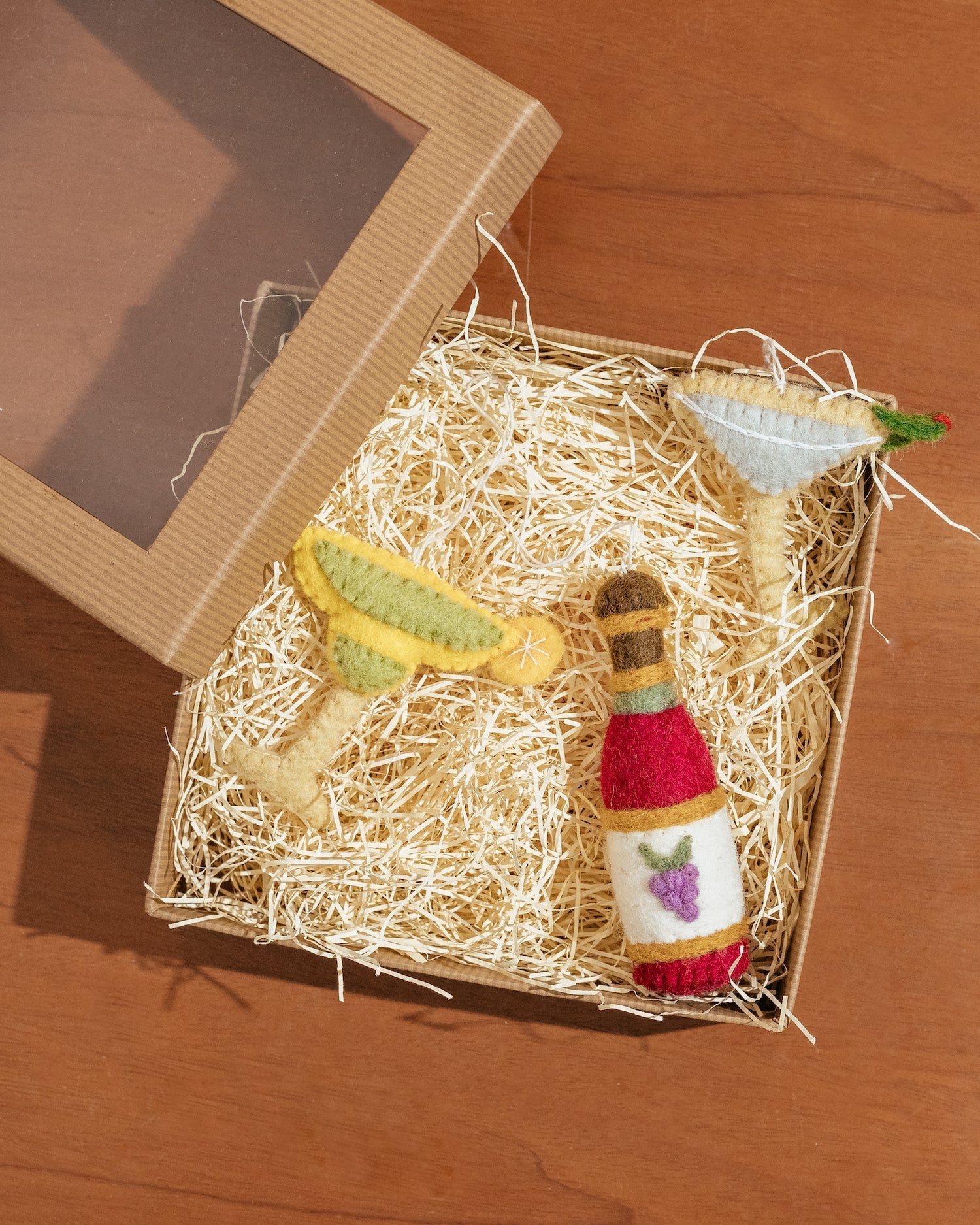 A gift box with felt ornaments of a wine bottle, a margarita, and a martini.