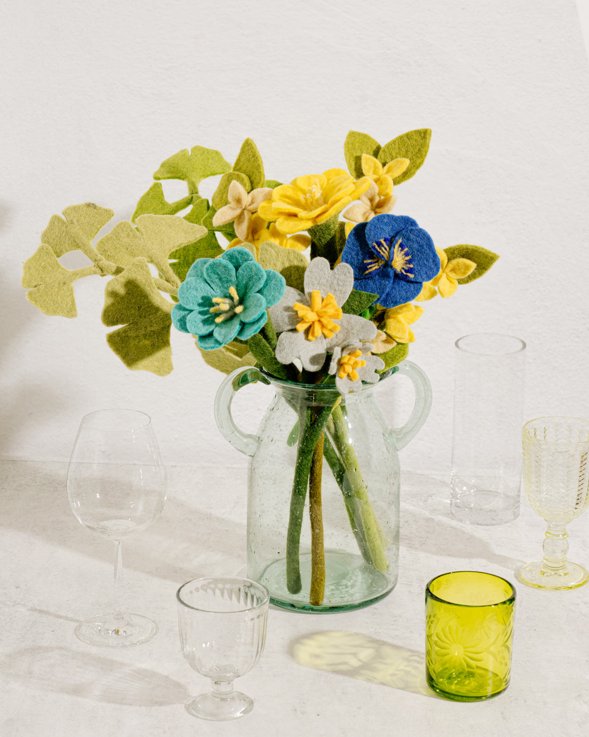 Felt Pansies in clear vase in yellow, white, and blue.
