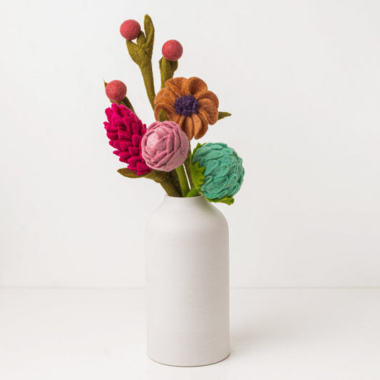 Pink and blue felt floral arrangement in a white vase.