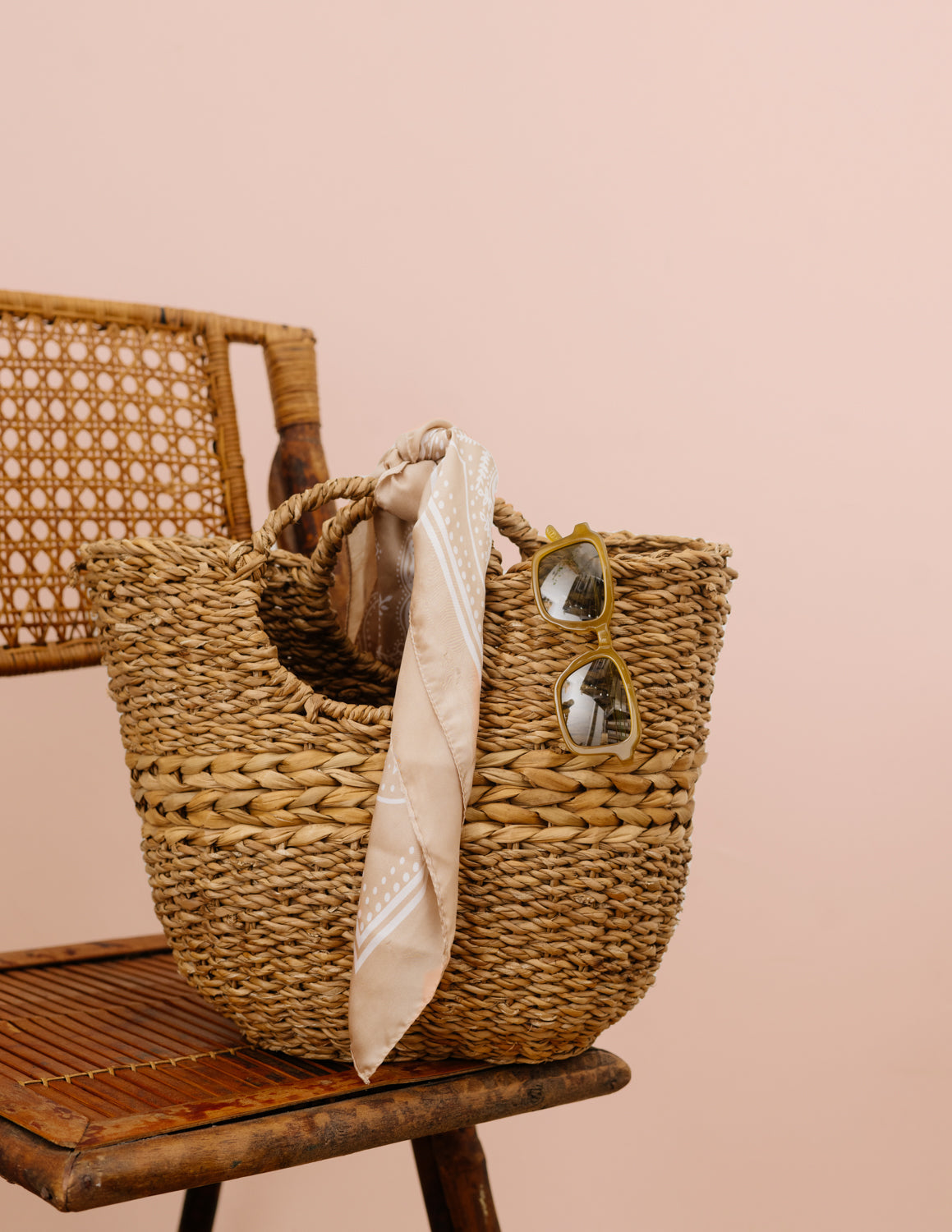 Brown woven basket with round handles on chair.