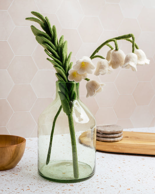 Felted white lily of the valley flower in glass vase.