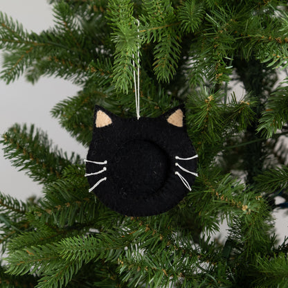 Felt ornament of a black cat face outline with a frame in the middle to put a photograph, hanging on a Christmas tree.