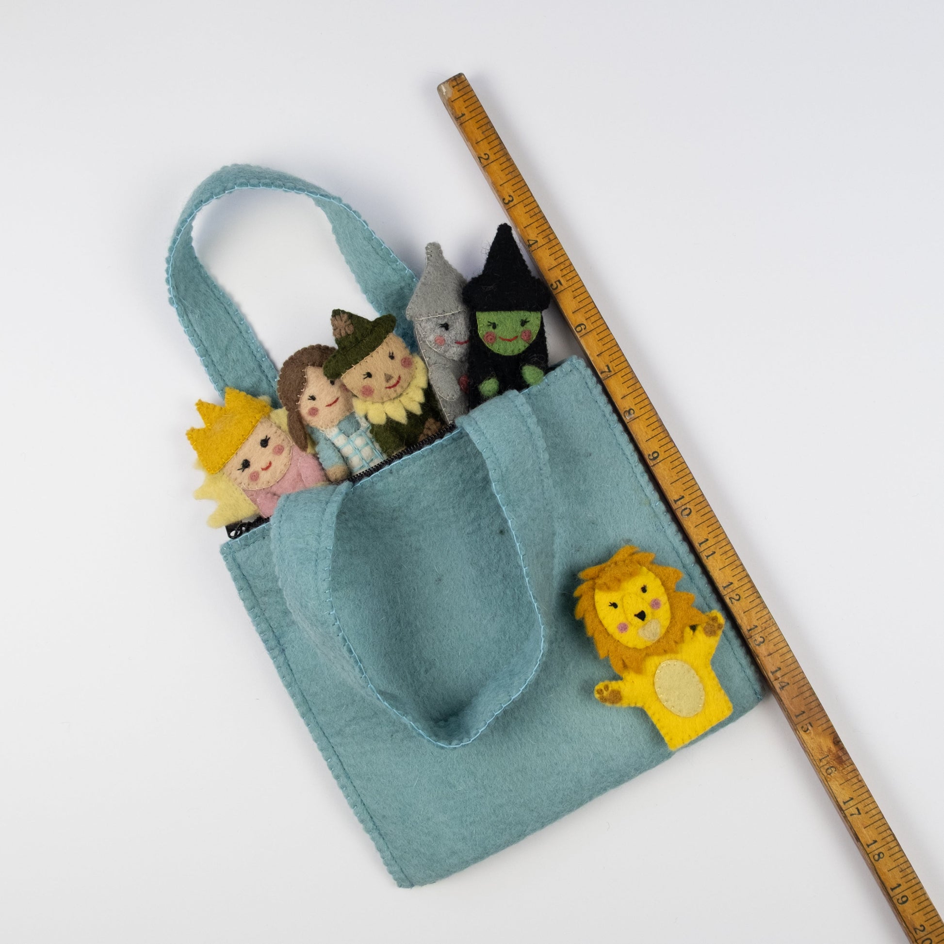 Back side of blue felt puppet bag for kids with wizard of oz themed characters of Dorothy, the Tin Man, The Cowardly Lion, Glinda the Good Witch, The Wicked Witch of the West, and the Scarecrow.