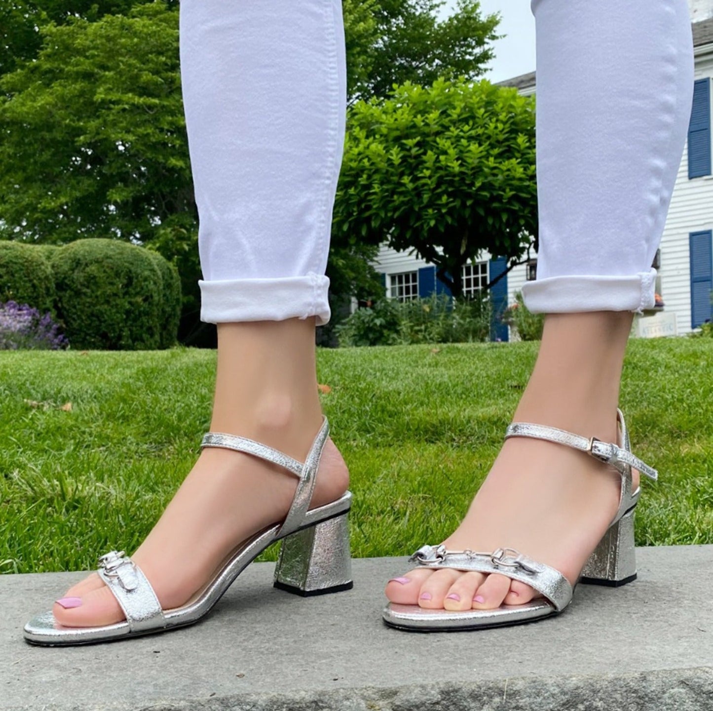 Closeup of woman wearing silver sandals and jeans.