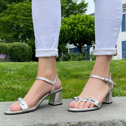 Closeup of woman wearing silver sandals and jeans.