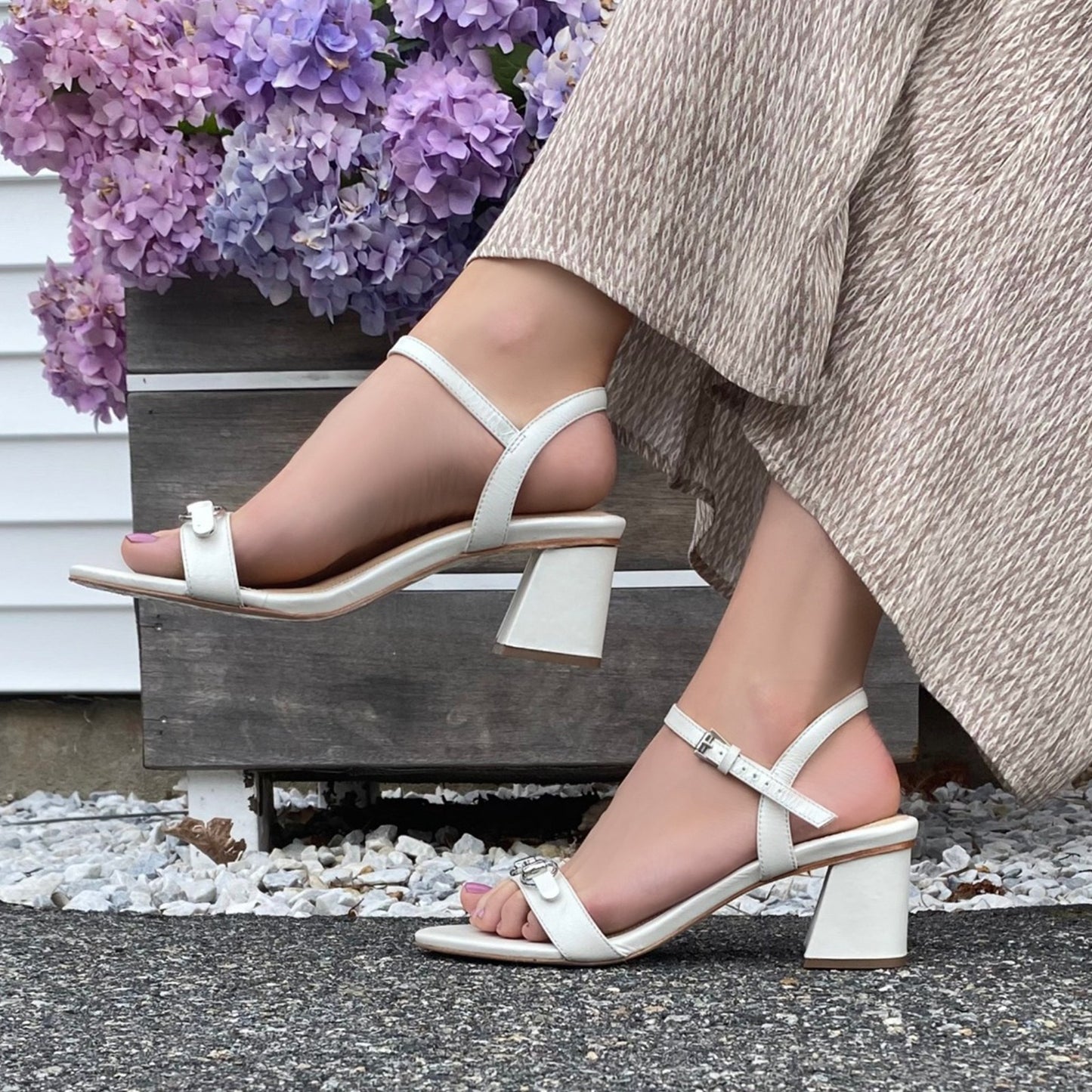 Closeup of woman wearing pearl sandal and natural pants.