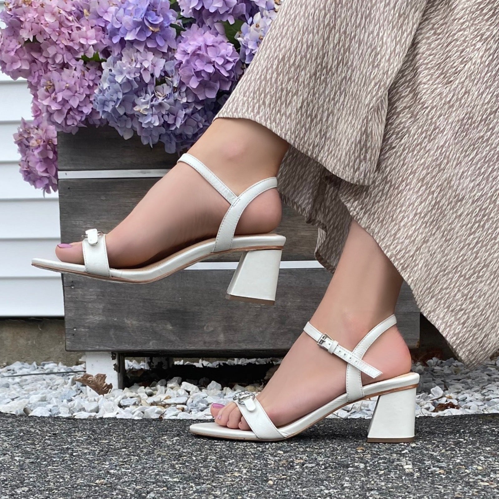 Closeup of woman wearing pearl sandal and natural pants.