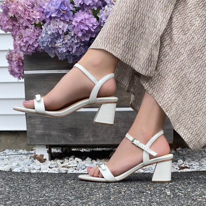 Closeup of woman wearing pearl sandal and natural pants.