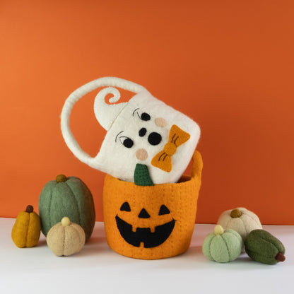 Orange felt jack-o-lantern trick-or-treat bucket and a white felt ghost trick-or-treat bucket with orange bow tie on top and felt pumpkins beside them.
