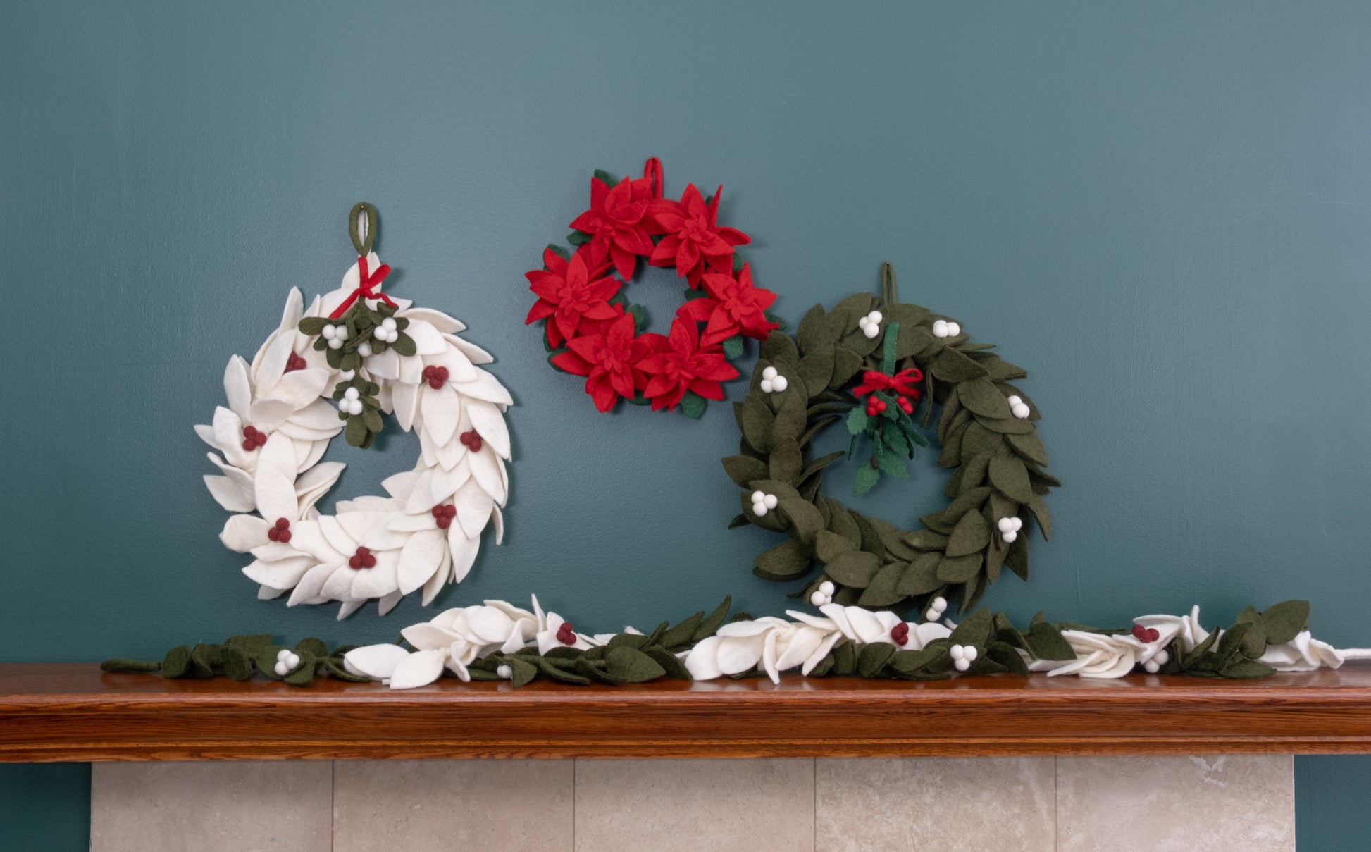 Felt ornament of Holly with berries and a red bow hanging with various wreaths.