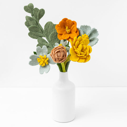 Yellow, orange, pink, green felt floral arrangement in a white vase.