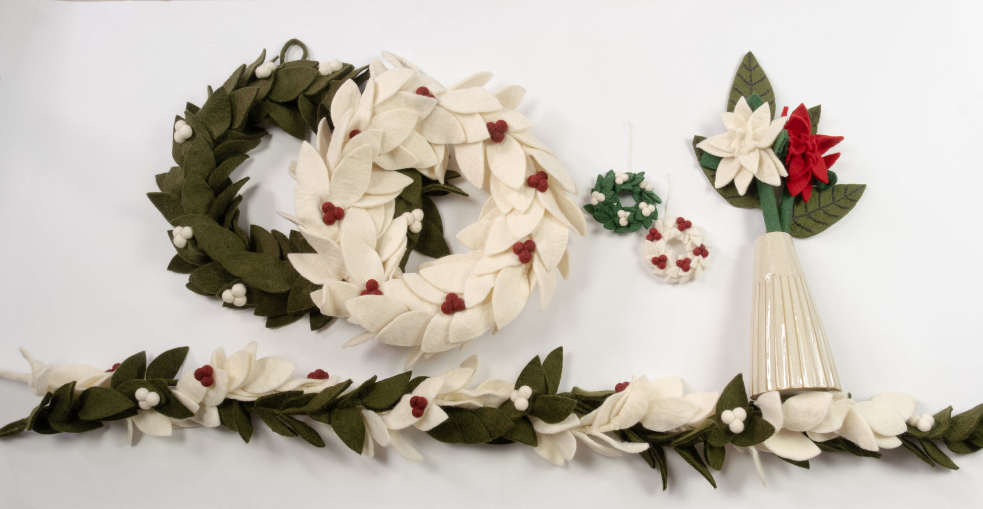 Various felt green, red and white wreaths, flowers, and garlands laid out.