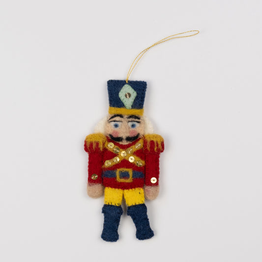 Felt ornament of a red and gold nutcracker.