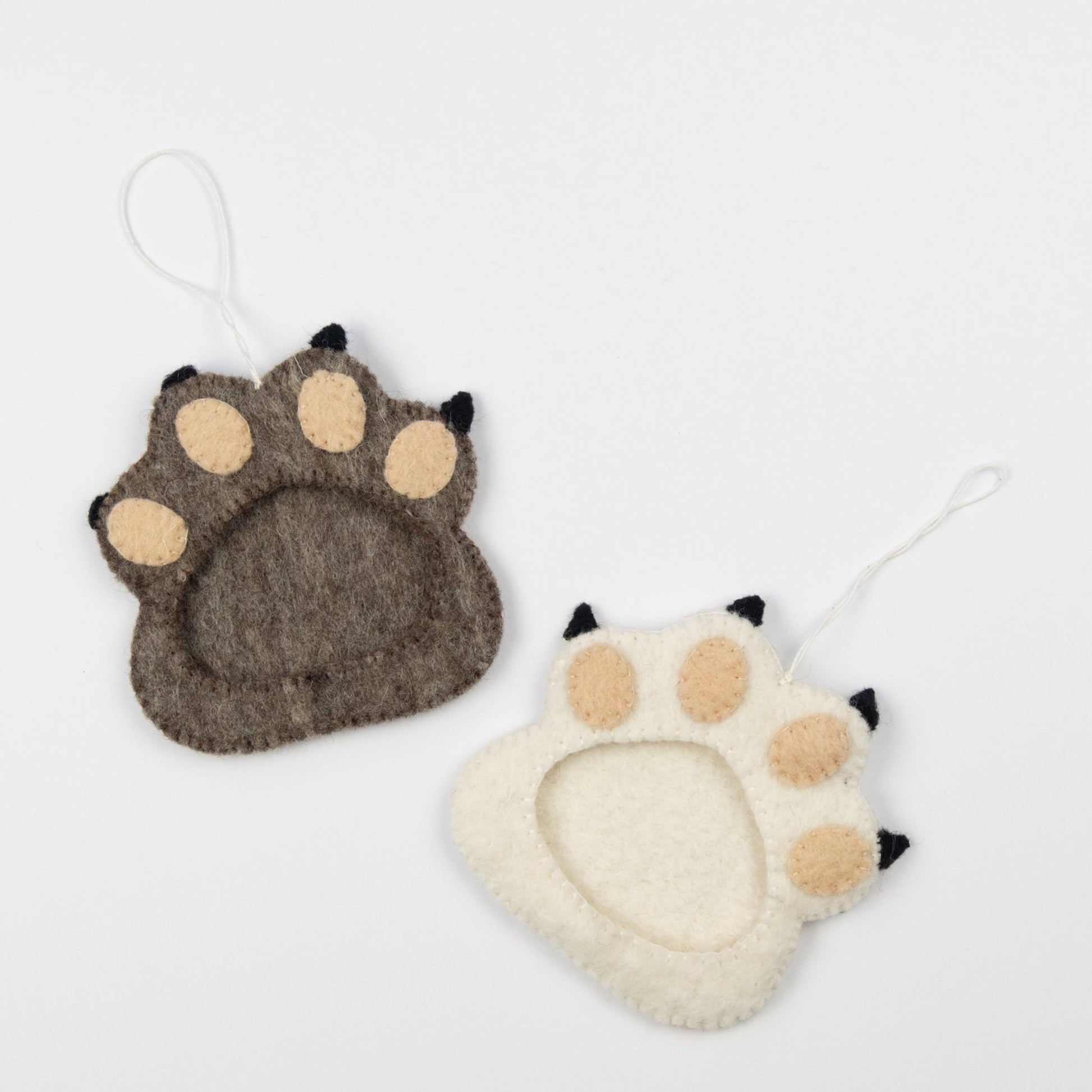 Felt ornaments of one brown and one white pawprint with a frame in the middle.