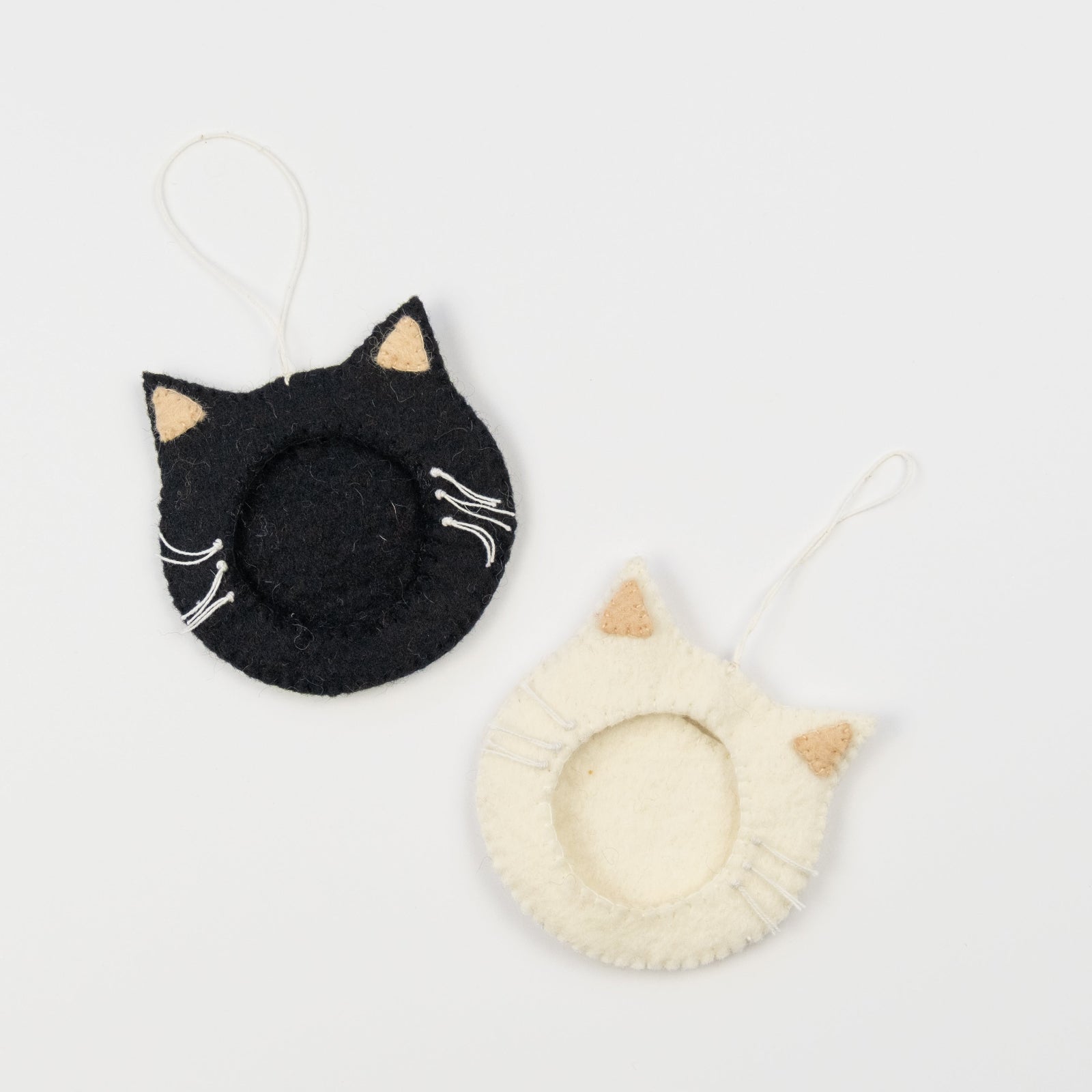 Felt ornaments of one black and one white cat face with a frame in the middle to put a photograph.
