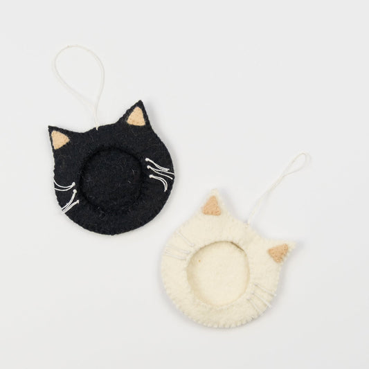Felt ornaments of one black and one white cat face with a frame in the middle to put a photograph.