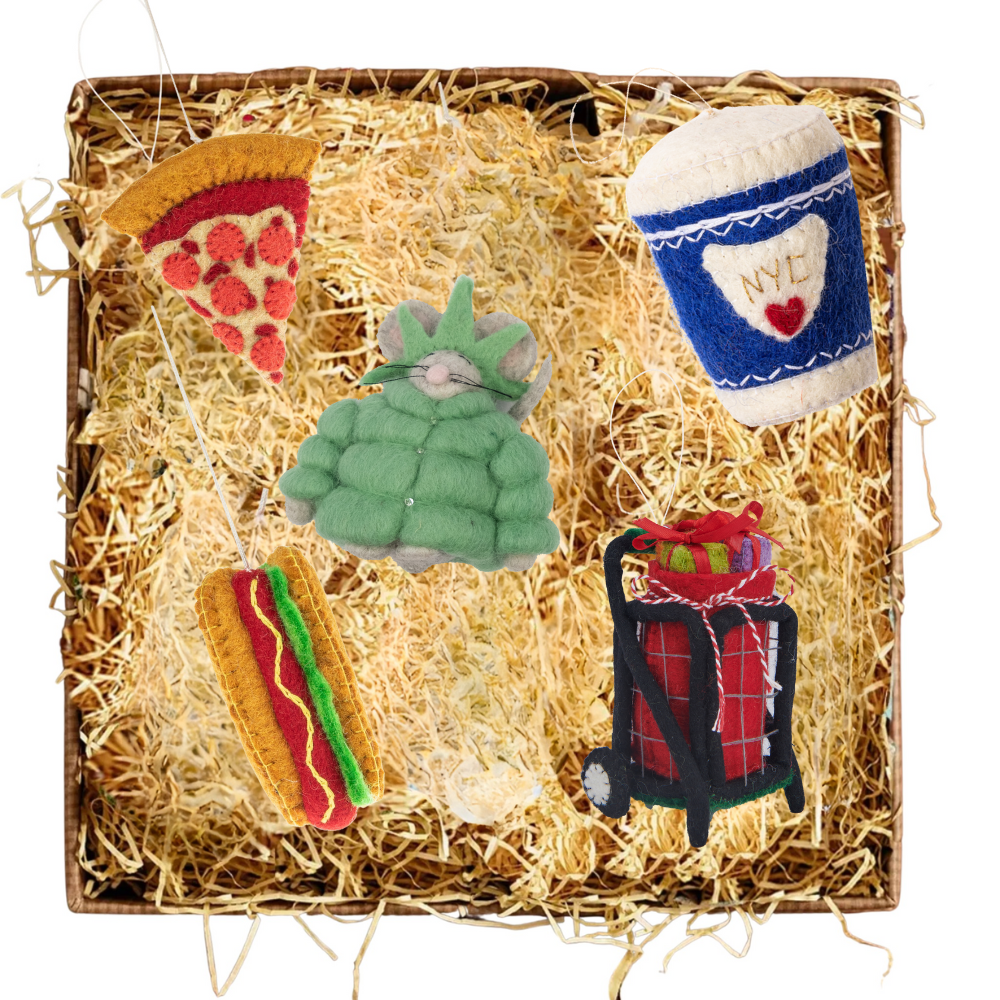 New York City themed felt Christmas ornaments featuring a to go coffee cup, a slice of pizza, a mouse in a Statue of Liberty puffer jacket, a hot dog, and a red granny cart with presents.