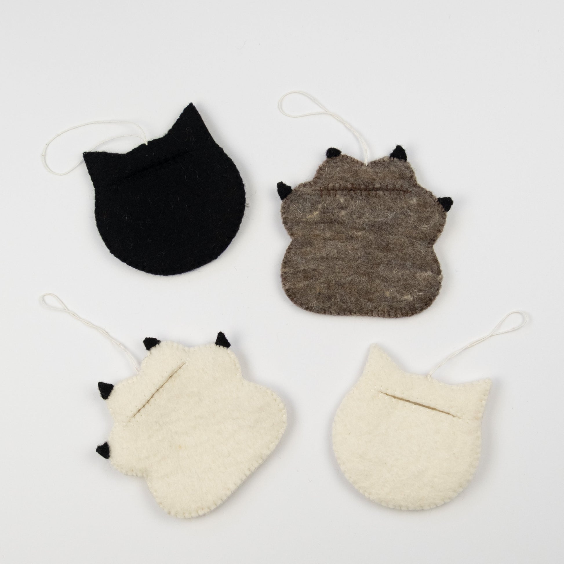 Back view of felt ornaments of a white pawprint, a black cat, a brown pawprint, and a white cat.