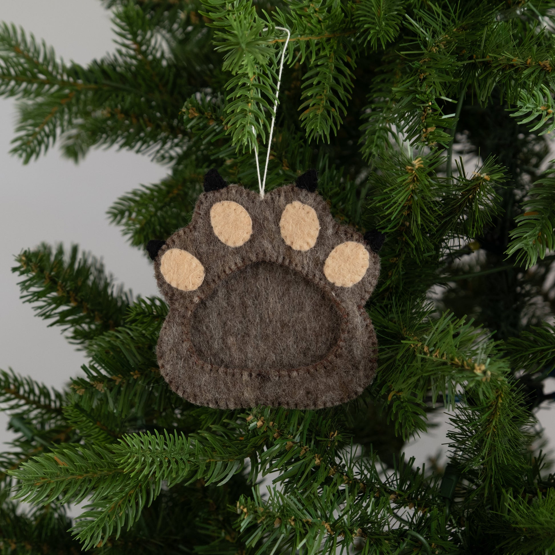 Felt ornament of brown paw print with a frame in the middle.