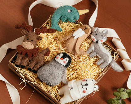 Felted wool ornaments of a narwal, walrus, fox, moose, penguin, and polar bear in a box.