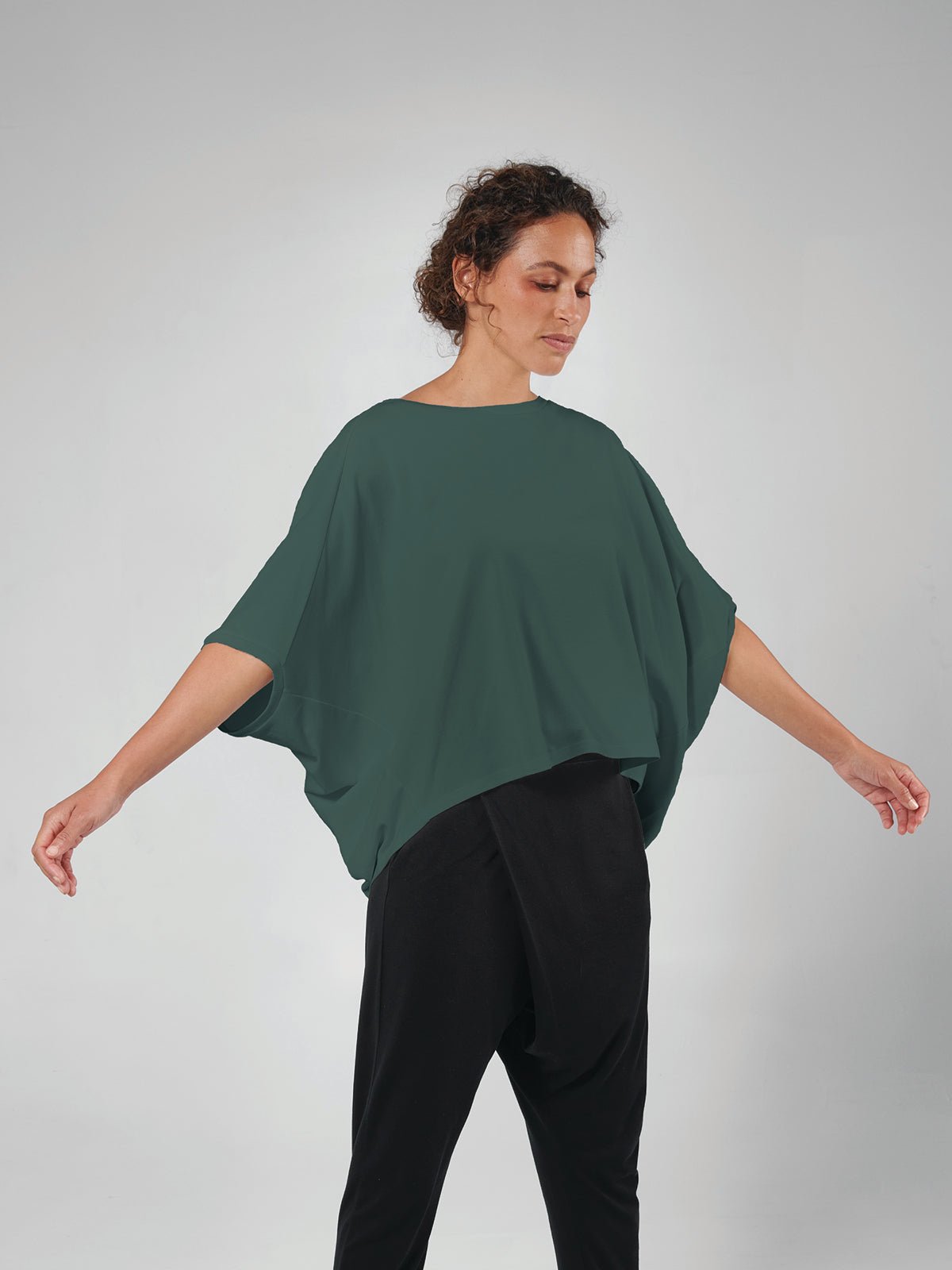 Woman wearing a green top and black pants on a white background