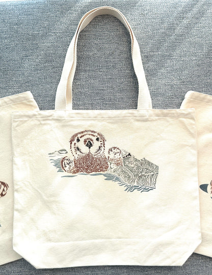 Canvas tote bag with picture of otter pup wrapped in seaweed.