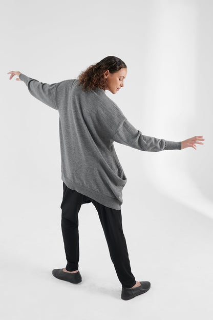 Back view of woman wearing grey cardigan, arms spread out.