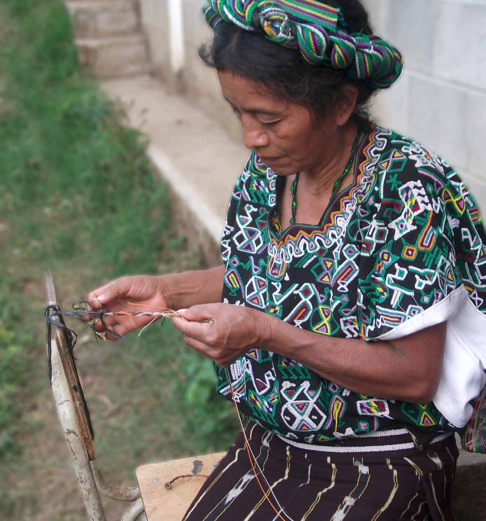 Indigenous woman in floral dress crafting fair trade felt flowers.
