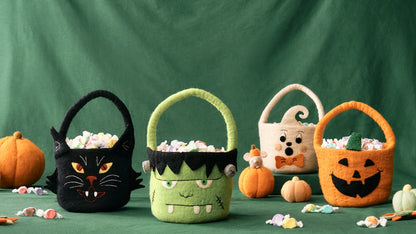 Four Halloween-themed candy baskets on a green background. Handmade by women artisans | Global Goods Partners