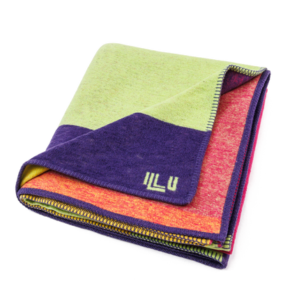 Blanket in bright purple, green, pink, and orange asymmetrical designs, folded neatly into a square.