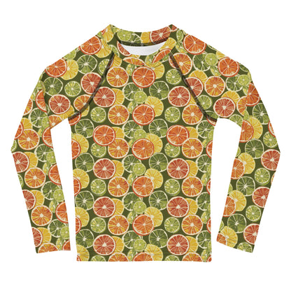 A vibrant citrus-themed rash guard for kids, featuring oranges and green leaves on a white background, shown from the front.