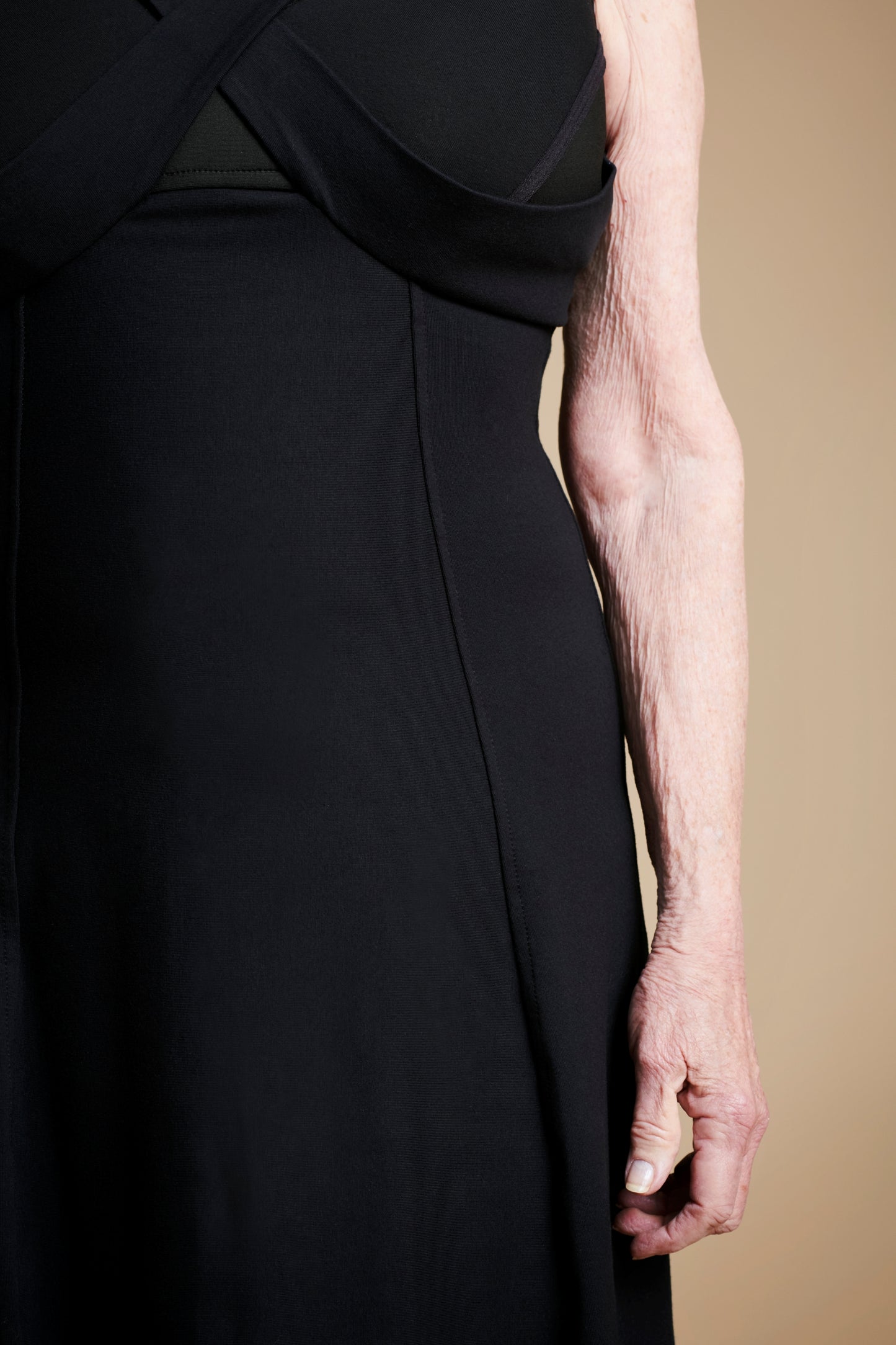 Closeup of front left arm of woman wearing long black dress.