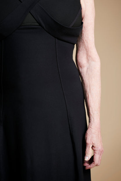 Closeup of front left arm of woman wearing long black dress.