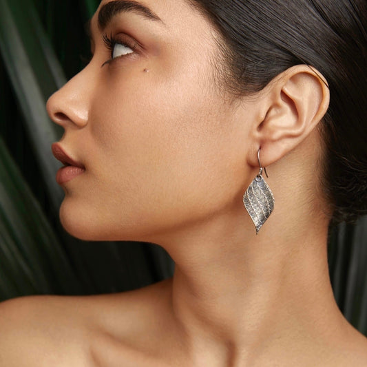 Left front view of woman wearing silver leaf earrings.