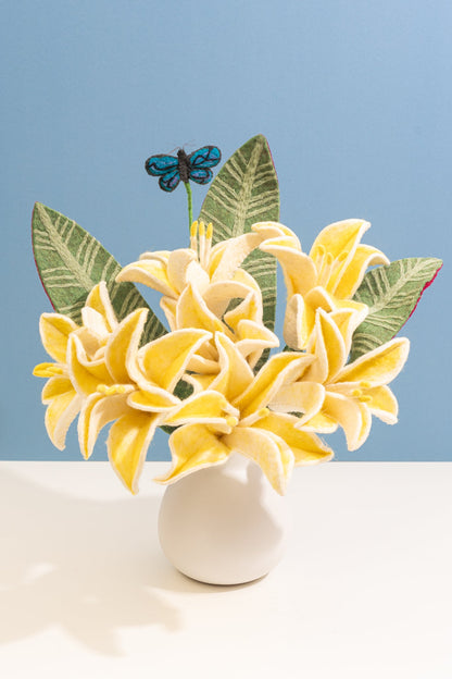 Handmade felt yellow flowers in a white vase with green leaves and a blue butterfly on a light blue background, all fair trade | Global Goods Partners