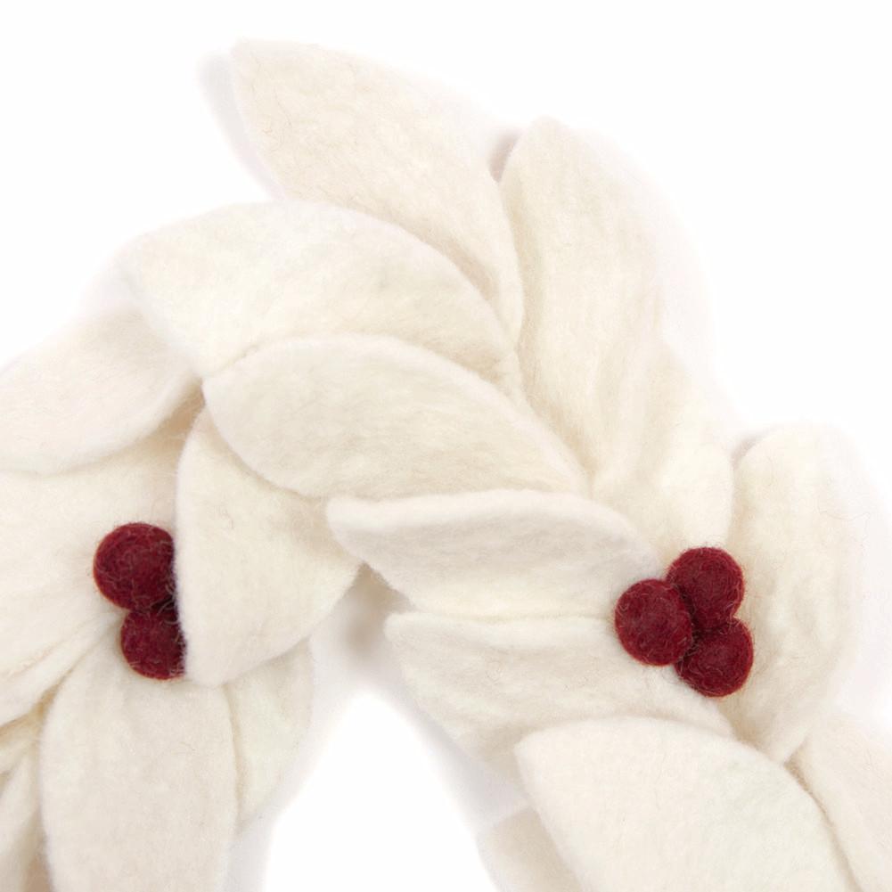 Close up of felt garland with white leaves with red berries.