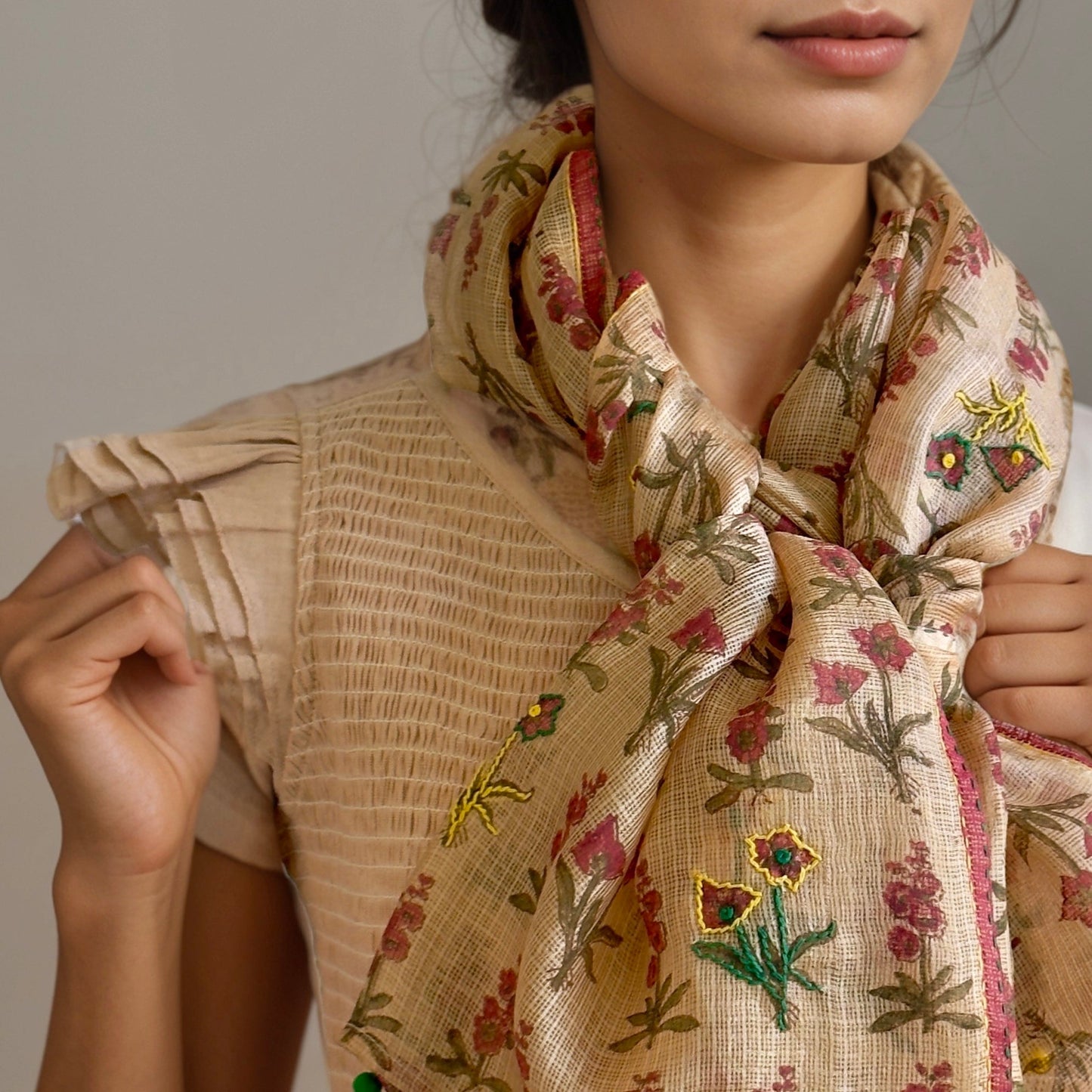 Front closeup of woman wearing natural dyed scarf with pink, green, yellowl flowers.