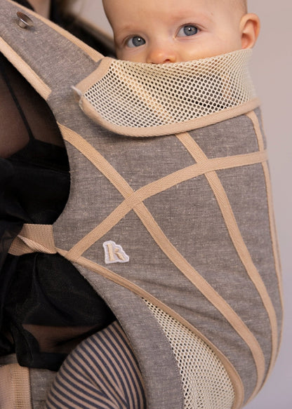 Closeup of baby in grey with tan stripes baby carrier.