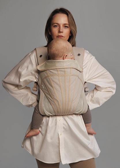 Woman carrying baby on chest in a baby carrier. Woman is wearing white shirt.