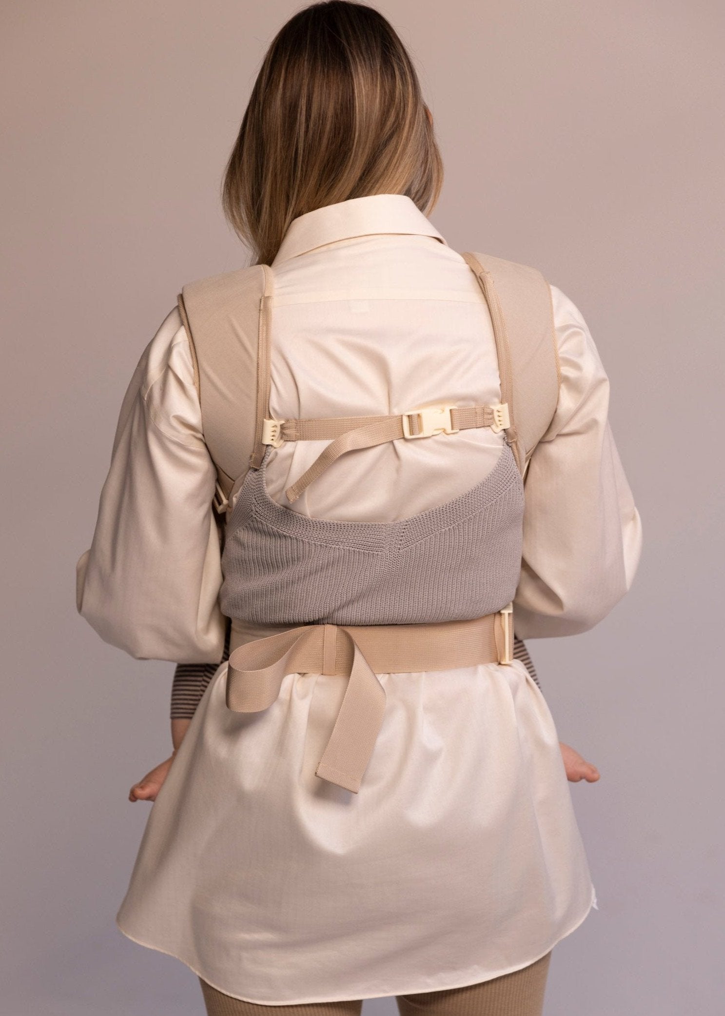 Back view of woman wearing corset baby carrier.